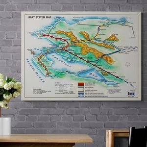May include: A rectangular wall print featuring the BART System Map of the San Francisco Bay Area. The map displays transit lines in red, yellow, green, and blue, with topographical terrain, water bodies, and a legend detailing route information.