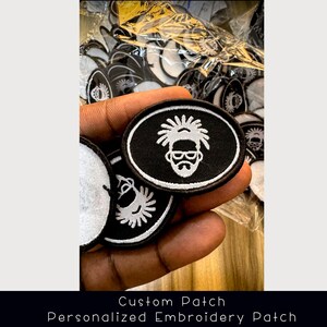 May include: Oval-shaped black and white embroidered patches. Each patch has a white outline and a white graphic of a person with glasses and a beard on a black background. The text "Custom Patch, Personalized Embroidery Patch" is at the bottom.