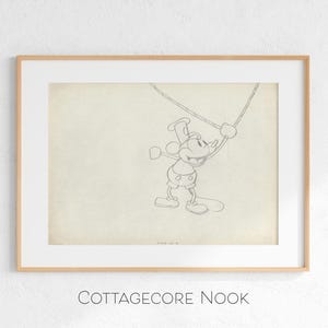 May include: Framed black and white sketch of a cartoon mouse character, holding onto a rope. The artwork is in a light-colored frame with a white mat. The text "COTTAGECORE NOOK" is at the bottom of the frame.