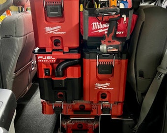 May include: A red Milwaukee Packout tool box with a black handle and a black and red Milwaukee Fuel brushless vacuum cleaner stacked on top of it. The tools are in the back of a white truck.