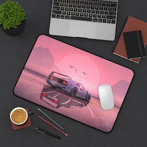 May include: A pink and white mousepad with a white sports car driving on a road with a sunset in the background. The mousepad has a white mouse on it.