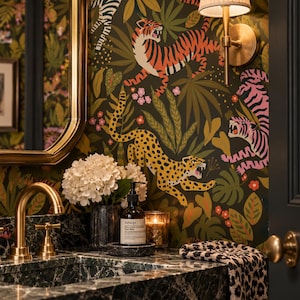 May include: A bathroom vanity area featuring dark green marble countertops, a brass faucet, and wallpaper with a jungle pattern of tigers and leopards. Includes a white hydrangea bouquet, an Aesop hand wash bottle, a candle, and a leopard print towel.