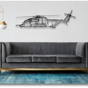 May include: A black metal silhouette of a helicopter hanging on a white wall above a gray sofa with gold legs. The sofa is in front of a blue rug.