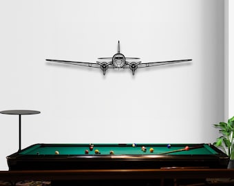 May include: Black metal airplane wall art. The airplane is a vintage design with two propellers and a detailed outline. The art piece is mounted on a white wall above a pool table with colorful billiard balls.
