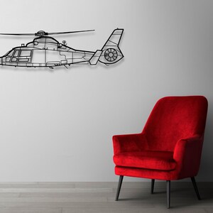 Peut inclure: Une sculpture de m&eacute;tal noir en forme d'h&eacute;licopt&egrave;re suspendue &agrave; un mur blanc au-dessus d'un fauteuil en velours rouge.