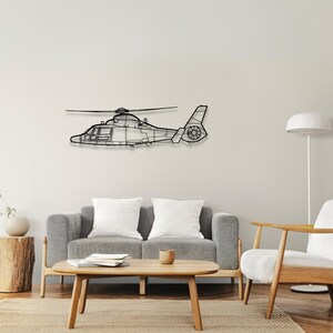 Peut inclure: Une silhouette noire en m&eacute;tal d'un h&eacute;licopt&egrave;re sur un mur blanc. L'h&eacute;licopt&egrave;re est en vol avec les pales du rotor d&eacute;ploy&eacute;es. L'h&eacute;licopt&egrave;re est accroch&eacute; au mur au-dessus d'un canap&eacute; gris et d'un fauteuil blanc.