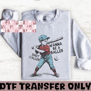 May include: Gray sweatshirt with a graphic of a cartoon baseball player holding a bat and the text "Wanna be a baller" and "Shot caller".