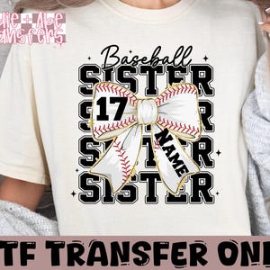 May include: White t-shirt with black text that reads "Baseball Sister" with a baseball-themed bow and the number 17. The text "Name" is written on the bow.