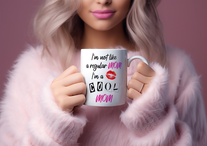 Blonde stylish mom in pink sweater holding white coffee mug with the mean girls quote I'm not a regular mom I'm a cool mom.