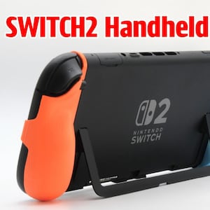 以下が含まれることがあります： オレンジと青のアクセントが付いた黒いNintendo Switchハンドヘルドグリップ。「SWITCH2 Handheld grip」の文字が赤色で上部に表示されています。Nintendo Switchのロゴがデバイスの背面に表示されています。