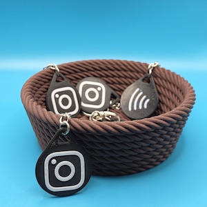 May include: A brown woven basket filled with black keychains featuring the Instagram logo and a wifi symbol.