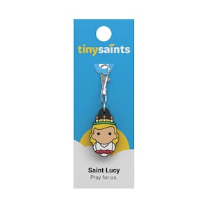 May include: A blue and white card with the text "tinysaints" on it. A silver keychain with a black and yellow cartoon image of Saint Lucy, with the text "Saint Lucy Pray for us."