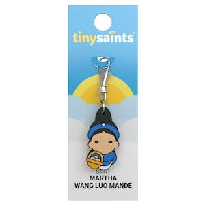 May include: A blue and yellow keychain with a cartoon image of Saint Martha Wang Luo Mande, a tiny saints character. The keychain has a silver clip.