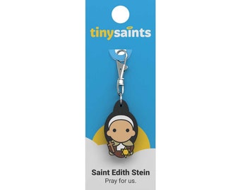 May include: A blue and yellow keychain featuring a black and white cartoon image of Saint Edith Stein. The keychain has a silver clip and the text "tinysaint" is printed on the card. The text "Saint Edith Stein" and "Pray for us." is printed below the image.