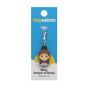 May include: A blue and yellow card with the words "tinysaint" printed on it. A silver keychain with a blue, red, and brown charm of Mary, Undoer of Knots. The text "Pray for us." is printed below the charm.