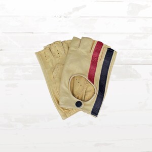 Peut inclure: Une paire de gants sans doigts en cuir beige avec un design à rayures rouges et bleu marine. Les gants ont une fermeture à bouton et de petits trous de ventilation. Les gants sont conçus pour la conduite ou d'autres activités.