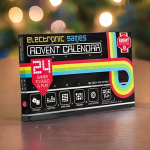Op de afbeelding: Electronic Games Adventskalender met 24 spellen om te bouwen en te spelen. De zwarte doos heeft kleurrijke regenboogstrepen en de tekst "Electronic Games Advent Calendar". Bevat spellen zoals Random, Reaction, Wire Maze, Memory en Codecracker. Voor kinderen vanaf 14 jaar.