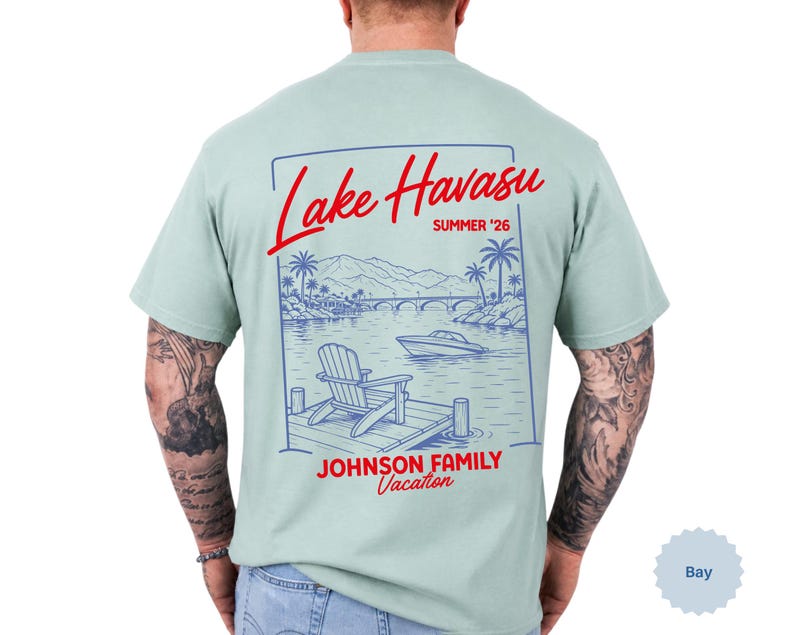 Puede incluir: Una camiseta verde claro con un gr&aacute;fico de l&iacute;neas azules en la espalda. El dise&ntilde;o muestra una escena de lago con una silla en un muelle, un barco y un puente. El texto rojo dice Lake Havasu, SUMMER '26 y JOHNSON FAMILY Vacation.