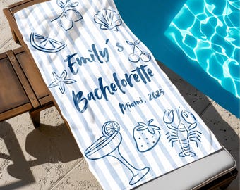 Puede incluir: Toalla de playa a rayas azules y blancas con el texto "Emily's Bachelorette Miami, 2025". La toalla presenta ilustraciones de una rodaja de limón, una concha, cerezas, una estrella de mar, un cóctel, una fresa y una langosta.
