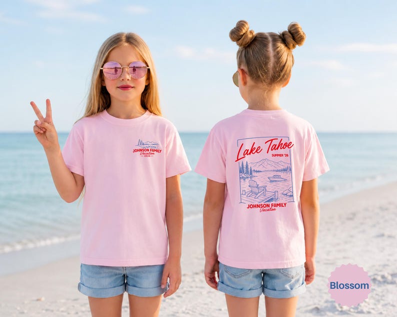 Puede incluir: Una camiseta de manga corta de color rosa claro con un peque&ntilde;o gr&aacute;fico en el pecho y un gr&aacute;fico grande en la espalda. El dise&ntilde;o posterior muestra una escena de lago con monta&ntilde;as, un barco y una silla, con el texto Lake Tahoe Summer 26.