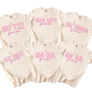May include: Six cream-colored short-sleeve t-shirts featuring pink plaid lettering and a goose graphic. The shirts display the text: AUTIE goose, GRAMPY goose, GRNDMA goose, GRMMY goose, MA MA goose, and DA DA goose in a consistent font style.
