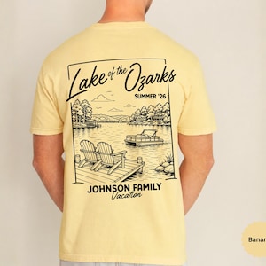 以下が含まれることがあります： 湖の風景の白黒グラフィックがプリントされた、明るい黄色のTシャツ。「Lake of the Ozarks SUMMER '26」と「JOHNSON FAMILY Vacation」の文字が入っています。2つの椅子が桟橋にあります。