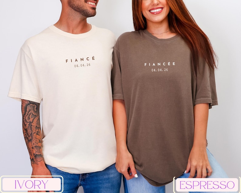 Puede incluir: Dos camisetas de manga corta, una marfil y otra espresso, cada una con la palabra "FIANC&Eacute;" o "FIANC&Eacute;E" y la fecha 04.04.26 impresa en la parte delantera. Las camisetas son de corte holgado, adecuadas para parejas.