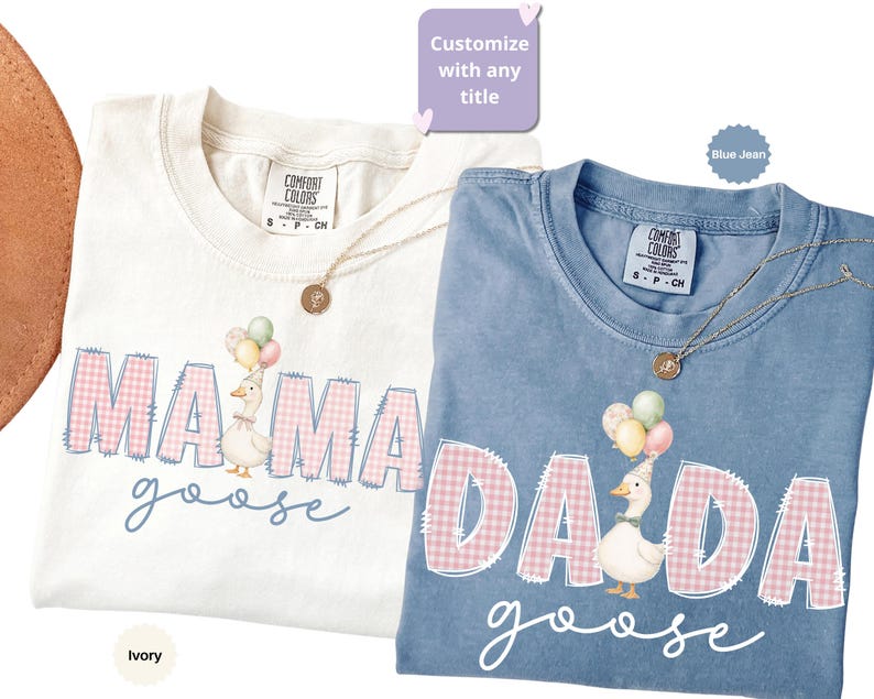 May include: Two short-sleeved t-shirts in ivory and blue jean colors. The ivory shirt features the text MAMA in pink gingham with a goose wearing balloons. The blue shirt features the text DADA in pink gingham with a goose wearing balloons.