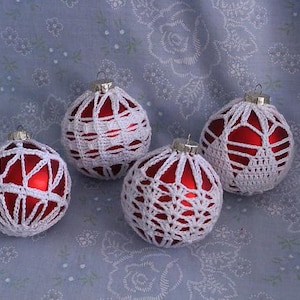 May include: Four red Christmas ornaments covered in white crocheted lace.