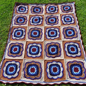 May include: A crocheted throw blanket with a repeating pattern of blue, brown, and white squares. The blanket is made with a textured yarn and has a scalloped edge.