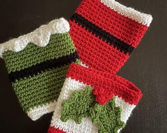 May include: Three handmade crochet cup cozies in festive colors. One is green with a black stripe and white trim, another is red with a black stripe and white trim, and the third is red, white, and green with green leaf accents.