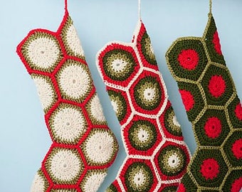 May include: Three crocheted Christmas stockings with a geometric pattern of red, green, and white hexagons.