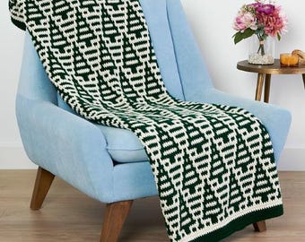 May include: A green and white crocheted throw blanket with a geometric pattern draped over a light blue armchair.