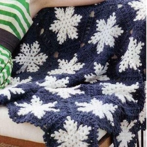 May include: A crocheted throw blanket with a snowflake pattern in white and navy blue.