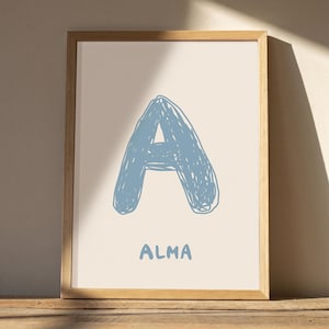 Könnte beinhalten: Ein gerahmter Druck mit einem großen, handgezeichneten, gekritzelten Buchstaben A in staubigem Blau, zentriert auf einem hellen cremefarbenen Hintergrund. Unter dem Buchstaben ist der Name ALMA in einer passenden, schlichten, serifenlosen Schrift.
