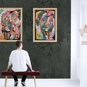 Puede incluir: Dos pinturas abstractas enmarcadas en una pared verde oscuro. La pintura de la izquierda presenta un dise&ntilde;o geom&eacute;trico colorido con m&uacute;ltiples caras. La pintura de la derecha presenta una sola cara con un dise&ntilde;o abstracto colorido.