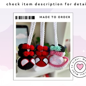 May include: Three crocheted keychains, each featuring a different character. The first keychain is red and black and resembles Spider-Man. The second keychain is red and black and resembles Spider-Man. The third keychain is pink and white and resembles a cartoon character. The keychains are hanging from white cords. The text "MADE TO ORDER" is visible at the top of the image.