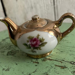 May include: A set of three ceramic mugs with a speckled, matte finish. The mugs are in shades of cream, light gray, and dark gray. Each mug has a simple, minimalist design and a rounded handle.