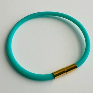 May include: A turquoise silicone bracelet with a gold metal clasp.