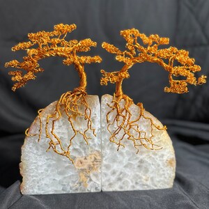 May include: A pair of gold wire tree bookends with white agate bases. The trees are stylized and have a whimsical look. The bases are natural and have a rough texture.