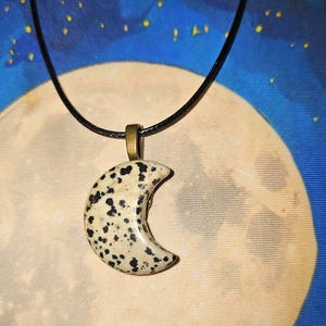 Crescent moon carved of Dalmation Stone. Included is a cord to wear it on. One of a kind.