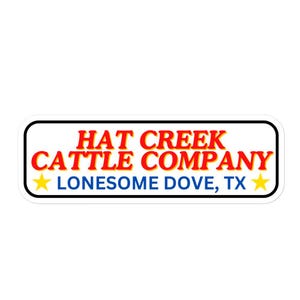 以下が含まれることがあります： 白地の長方形ステッカー。黒い縁取りがあり、「HAT CREEK CATTLE COMPANY」の文字は赤と黄色、「LONESOME DOVE, TX」の文字は青で書かれています。両側に黄色の星が2つあります。