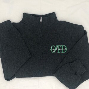 Heather black 1/4 quarter zip sweatshirt with custom embroidery featuring OTD in light green in all caps with name Sydnie in cursive font in white thread.