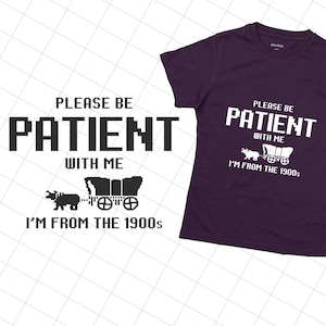 May include: Purple t-shirt with white text that reads "Please be patient with me I'm from the 1900s". The text is in a pixelated font and there is a small graphic of a covered wagon and a bull.