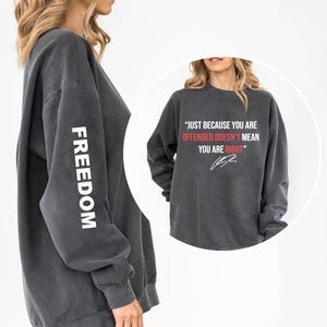 May include: Dark gray sweatshirt with the word "FREEDOM" printed vertically in white on the left sleeve. The right side of the sweatshirt has the quote, "JUST BECAUSE YOU ARE OFFENDED DOESN'T MEAN YOU ARE RIGHT" in red and white.