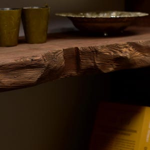 May include: A rustic wooden shelf with a live edge, displaying two olive green candle holders and a decorative bowl. The shelf's natural wood grain is prominent, and the items are arranged for a warm, inviting aesthetic.