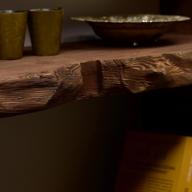 May include: A rustic wooden shelf with a live edge, displaying two olive green candle holders and a decorative bowl. The shelf's natural wood grain is prominent, and the items are arranged for a warm, inviting aesthetic.