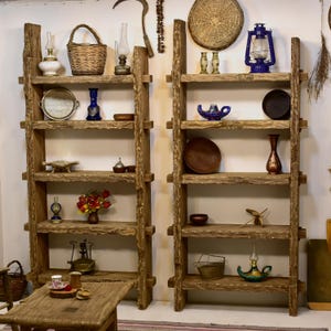 May include: Two rustic wooden shelves filled with decorative items. The shelves are made of rough-hewn wood and hold various objects, including baskets, vases, lanterns, and plates. The shelves are against a white wall, creating a warm, inviting display.