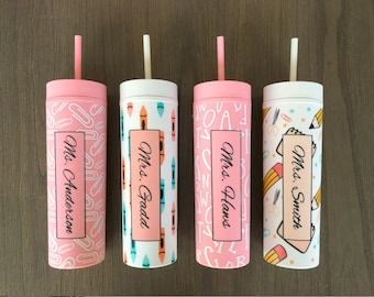 Può includere: Quattro bicchieri riutilizzabili rosa e bianchi con cannucce. Ogni bicchiere ha un design diverso con forniture scolastiche e il nome di un insegnante: "Sig.ra Anderson", "Sig.ra Gadd", "Sig.ra Hans" e "Sig.ra Smith".