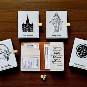 May include: White leatherette temple recommend holders with gold clasps. Designs include a temple, a figure of Jesus, a circle with a figure, and floral accents. One holder is open, revealing a passport and other documents.